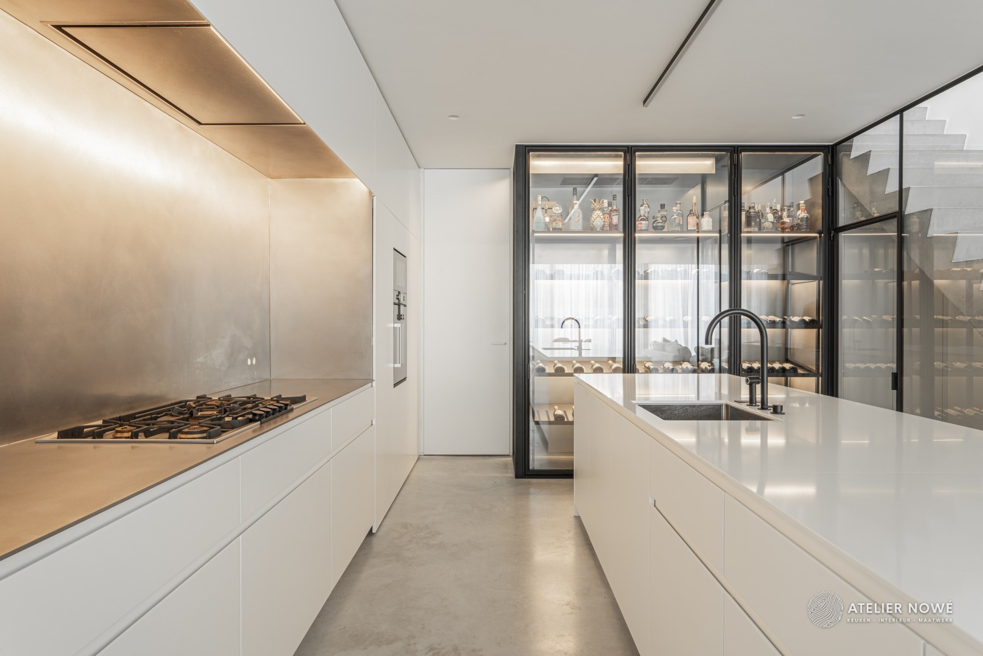 Keuken op maat in Astene met greeploze witte kasten, kookwand en werkblad in inox en een glazen wijnkast
